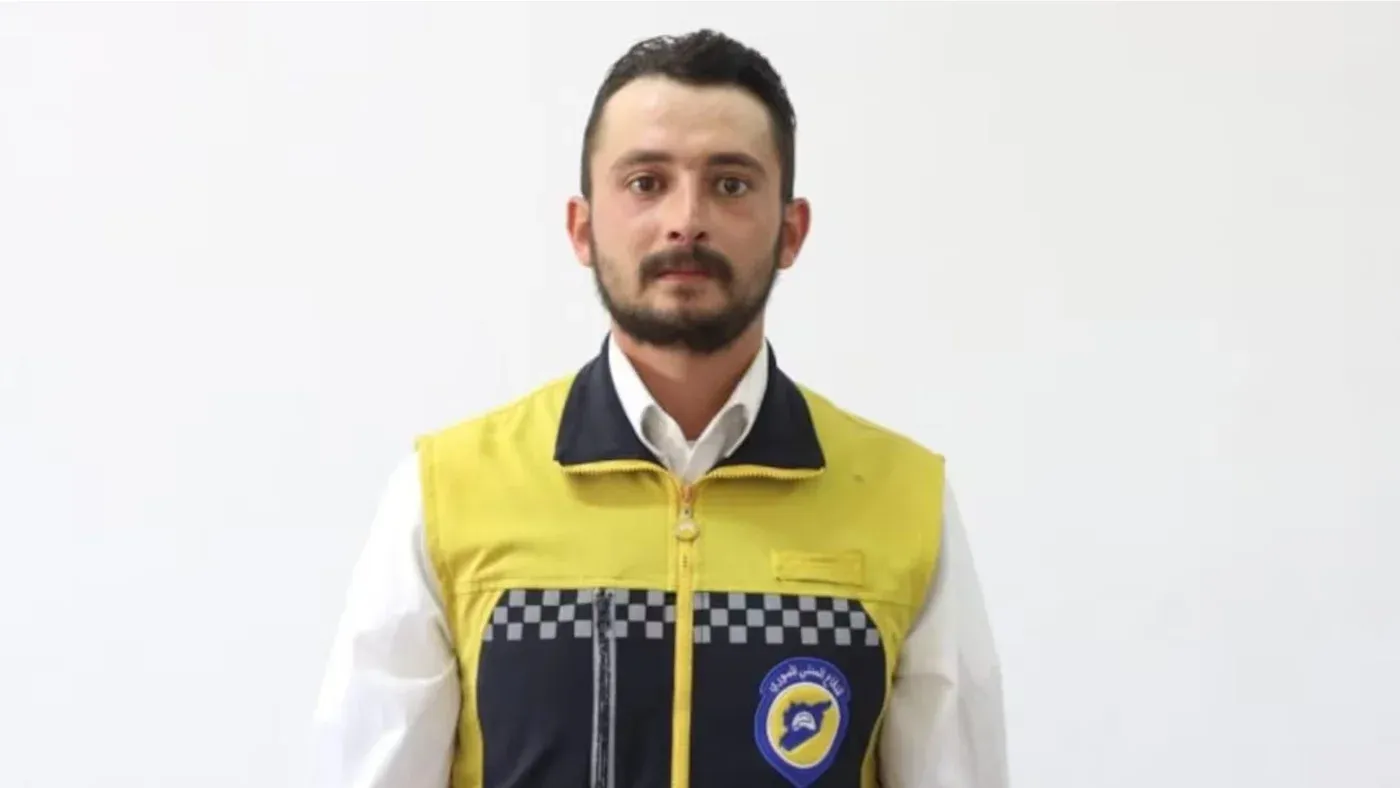 شاب سوري يرتدي زي الخوذ البيضاء للإنقاذ، يعكس قضية وفاة محمد غميرة في الحجز ومطالبات حقوق الإنسان بمحاسبة المسؤولين في سوريا.