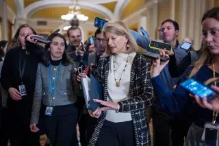 مجموعة من الصحفيين تتجمع حول عضو مجلس الشيوخ، حيث تتحدث عن القضايا المتعلقة بتمويل وزارة الأمن الداخلي ومطالب الديمقراطيين.