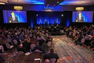 مناظرة بين جاسمين كروكيت وجيمس تالاريكو في مؤتمر نقابات عمال تكساس، حيث يتحدثان عن قضايا الهجرة والضرائب. الحضور يتفاعل مع المرشحين.