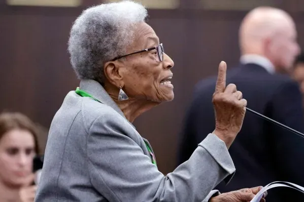 امرأة مسنّة تتحدث بحماسة خلال تجمع ديمقراطي في رالي، نورث كارولينا، معبرة عن معارضتها لإعادة رسم دوائر الكونغرس.