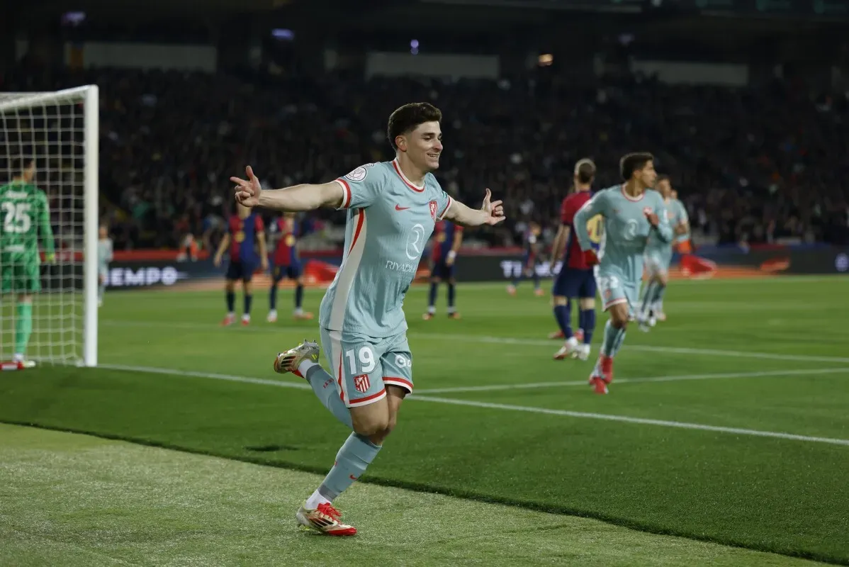 لاعب أتلتيكو مدريد يحتفل بتسجيل هدف خلال مباراة مهمة، مع وجود حارس مرمى خلفه، مما يعكس حماس ديربي مدريد.