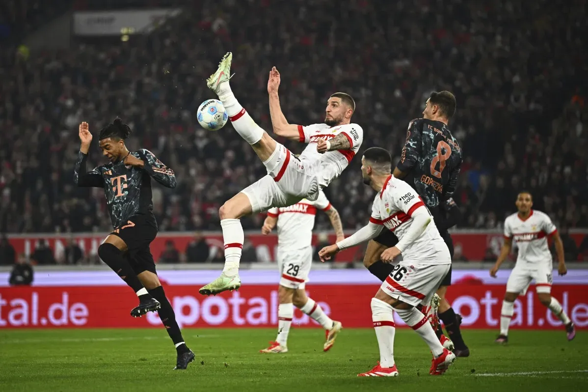 لاعب كرة قدم يقوم بحركة مثيرة أثناء مباراة، مع وجود لاعبين آخرين في الخلفية، مما يعكس الأجواء التنافسية في الدوري.