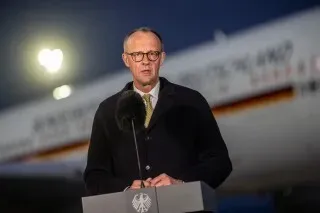 المستشار الألماني فريدريش ميرتس يتحدث أمام الصحافة في مطار بكين، مع طائرة خلفه، في إطار زيارته لتعزيز العلاقات مع الصين.