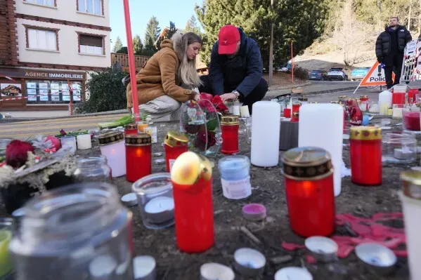شخصان يضعان الزهور والشموع في موقع تذكاري بعد حريق في حانة سويسرية، تأبينًا للضحايا الذين تعرضوا لإصابات خطيرة.