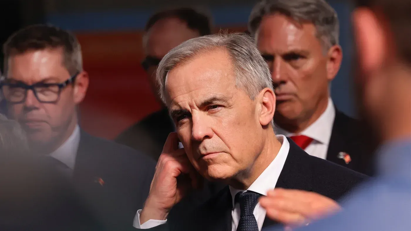 رئيس الوزراء الكندي مارك كارني يتحدث في مؤتمر صحفي، مع وجود مسؤولين آخرين في الخلفية، مع التركيز على قضايا السياسة الخارجية.