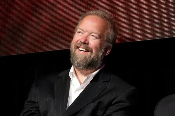 صورة لداون شليتس، كاتب الأغاني الأسطوري، مبتسمًا أثناء حدث في نيشفيل، مع خلفية ملونة تعكس أجواء الموسيقى.