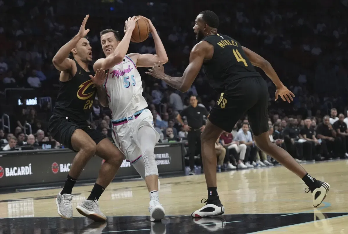 لاعبان من فريق كليفلاند كافالييرز يتنافسان مع لاعب من فريق ميامي هيت على الكرة خلال مباراة NBA، مما يعكس حدة المنافسة في اللقاء.