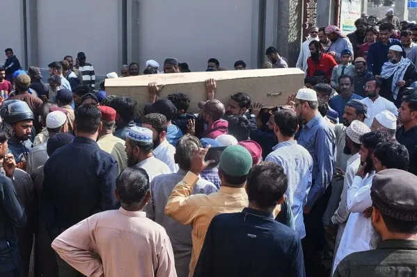 مشيعون يحملون نعشًا في جنازة شهروز إقبال، ضحية حريق كراتشي، وسط حشد من الناس في مشهد يعكس الحزن والألم.