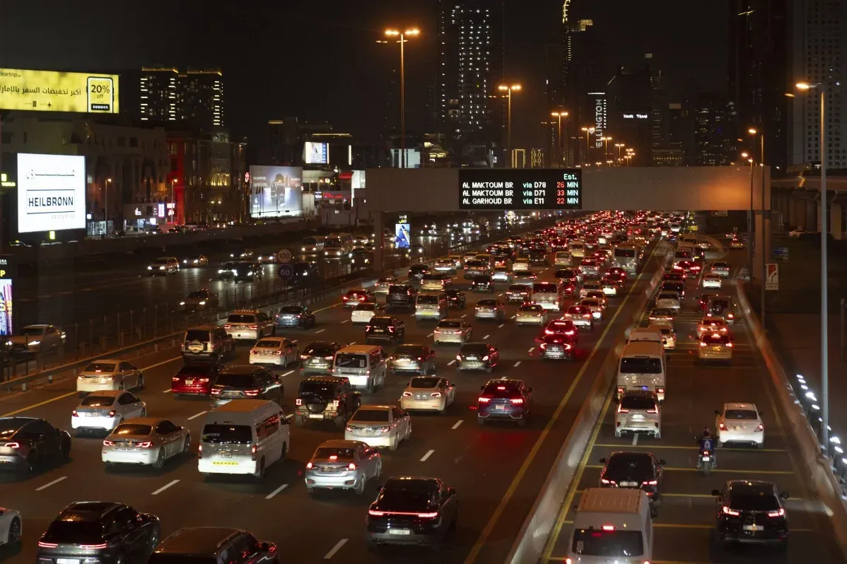 ازدحام مروري كثيف في دبي ليلاً، مع تكدس السيارات على الطريق وناطحات السحاب تضيء في الخلفية، يعكس التحديات الحضرية المتزايدة.