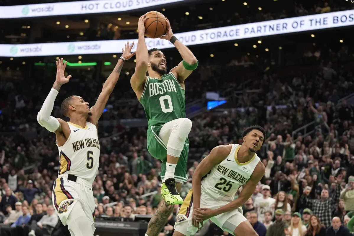 لاعب بوسطن جيسون تاتوم يسجل نقطة خلال مباراة كرة سلة، بينما يحاول لاعبان من نيو أورليانز اعتراضه.