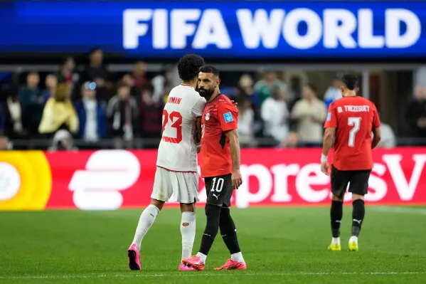 محمد صلاح يتحدث مع زميله بعد مغادرته الملعب بسبب إصابة في الركبة خلال مباراة مصر وإيران في كأس العالم، مما أثار قلقاً حول مشاركته المقبلة.
