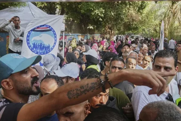 حشود من الناخبين المصريين في مركز اقتراع، مع وجود لافتة انتخابية في الخلفية، خلال انتخابات مجلس الشيوخ 2023.