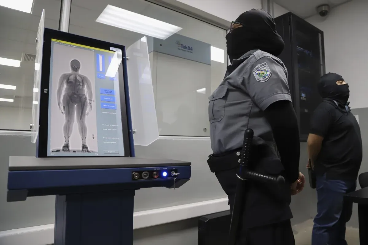 جهاز فحص بالأشعة السينية يُستخدم في السجون السلفادورية، مع حراس يرتدون أقنعة، لفحص السجناء بحثًا عن المواد المحظورة.