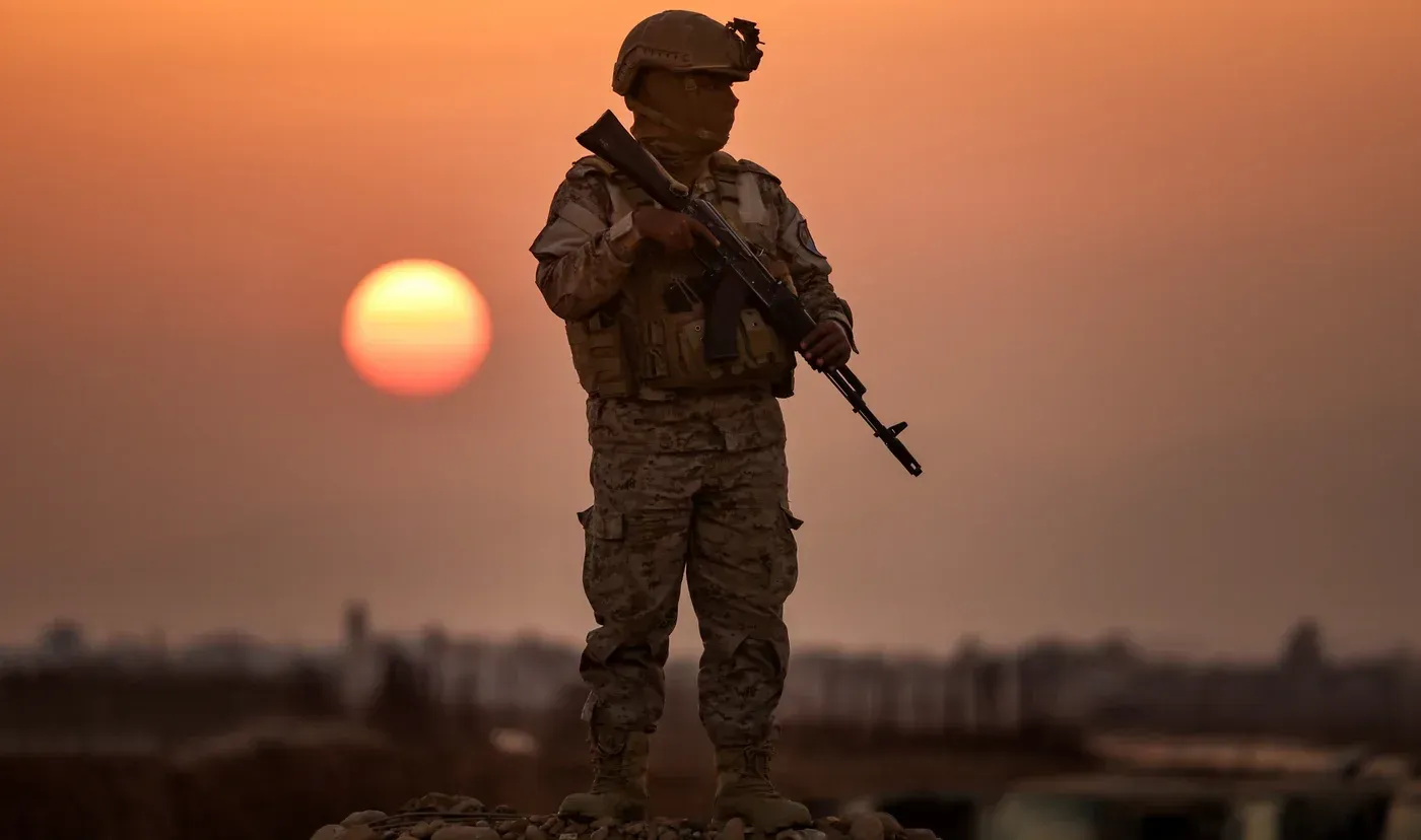 جندي يقف حاملاً سلاحه في موقعه، مع غروب الشمس في الخلفية، مما يعكس التحولات العسكرية في جنوب اليمن ودور قوات المقاومة الوطنية.