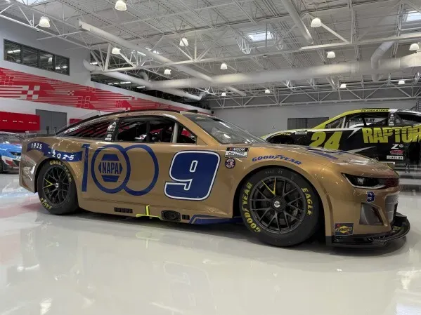 سيارة سباق تشيس إليوت بتصميم ذهبي احتفالاً بالذكرى المئوية لشركة NAPA، تحمل الرقم 9 وشعار الشركة، في مركز السباق.