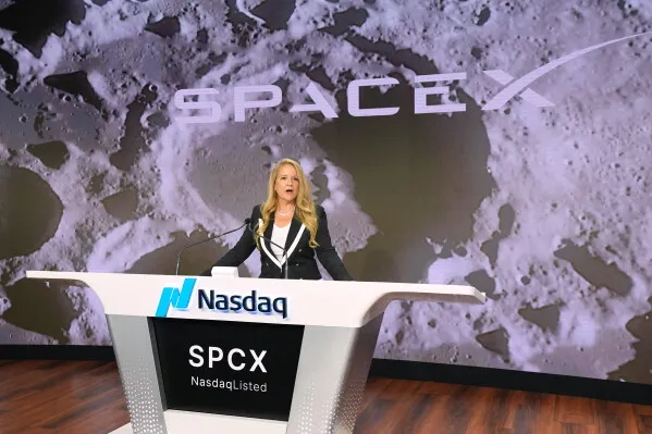 مراسم إطلاق الاكتتاب العام لشركة SpaceX في بورصة Nasdaq، حيث تظهر المتحدثة أمام شعار الشركة وخلفية فضائية، مما يعكس الطموحات الكونية لـ Elon Musk.
