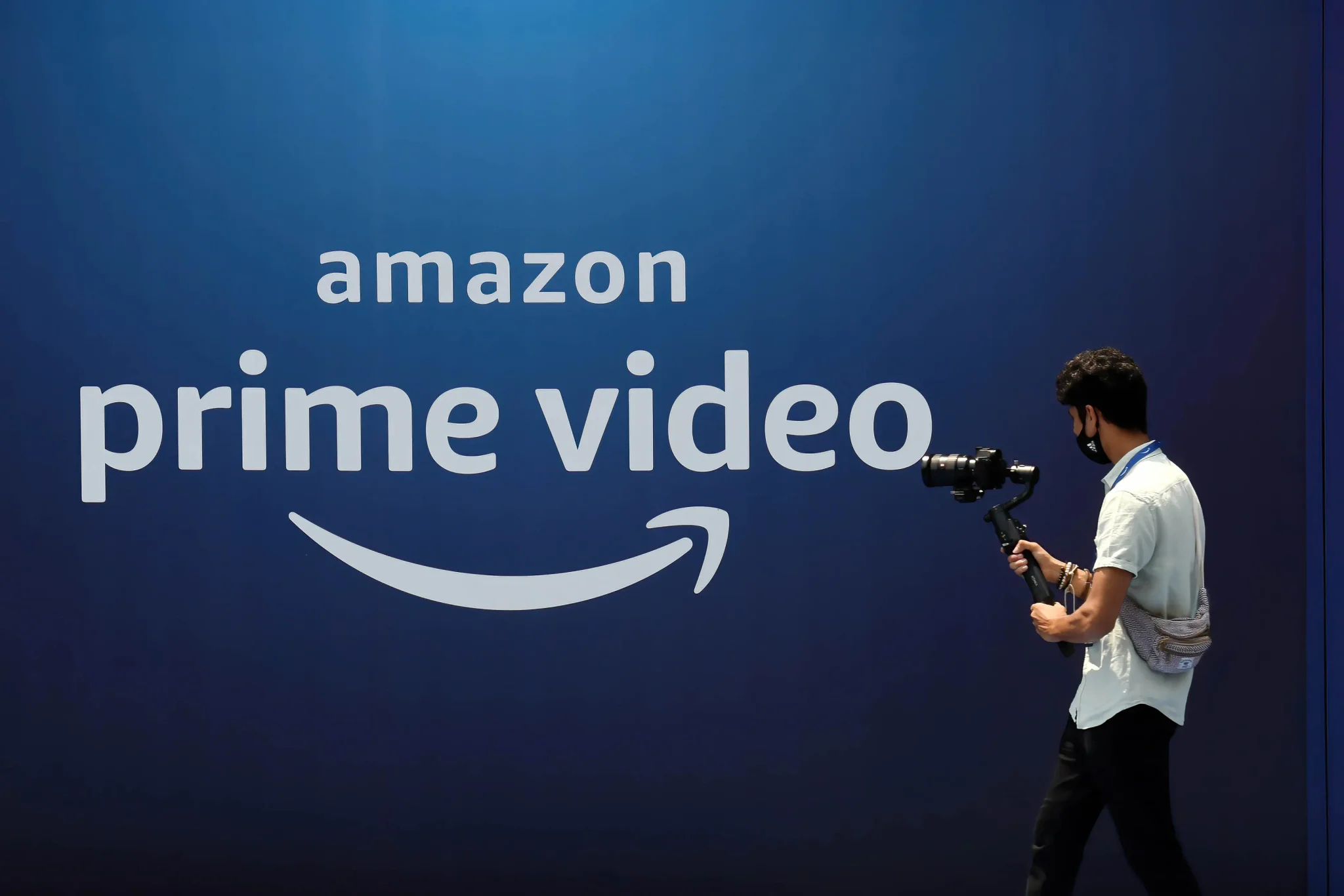 شعار Amazon Prime Video على خلفية زرقاء مع مصوّر يحمل كاميرا، يرمز إلى بث حفل جوائز الإيمي عبر المنصة الرقمية عالمياً.