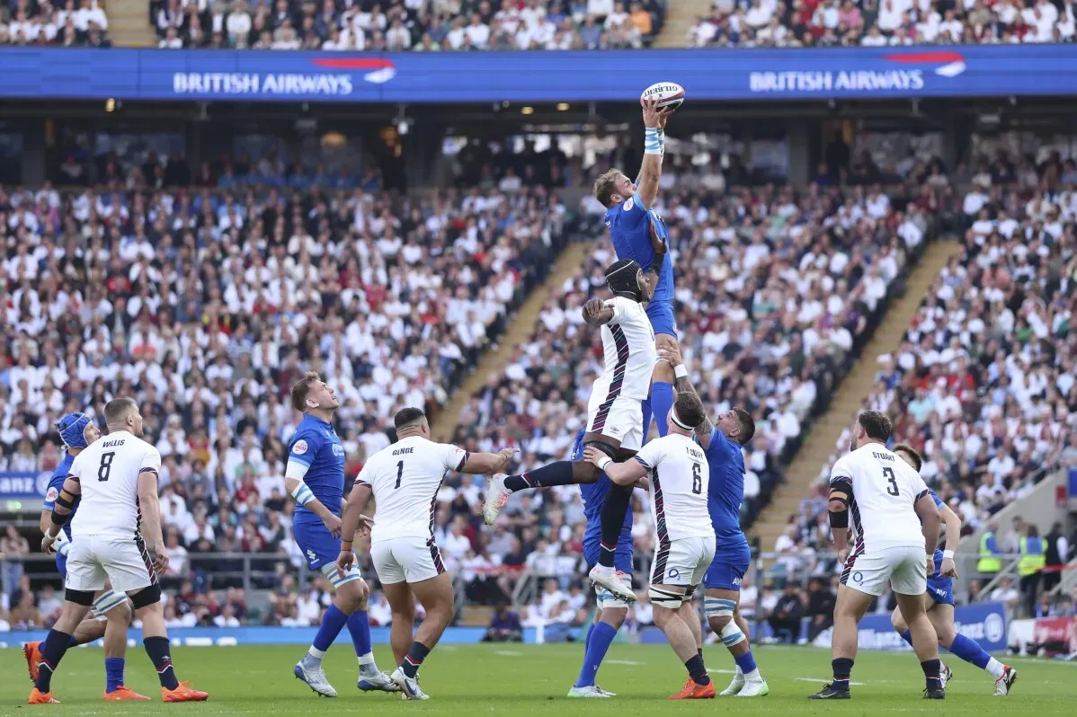 لاعب إيطالي يقفز عالياً لالتقاط الكرة خلال مباراة الرجبي ضد إنجلترا في تويكنهام، وسط حشد جماهيري كبير.