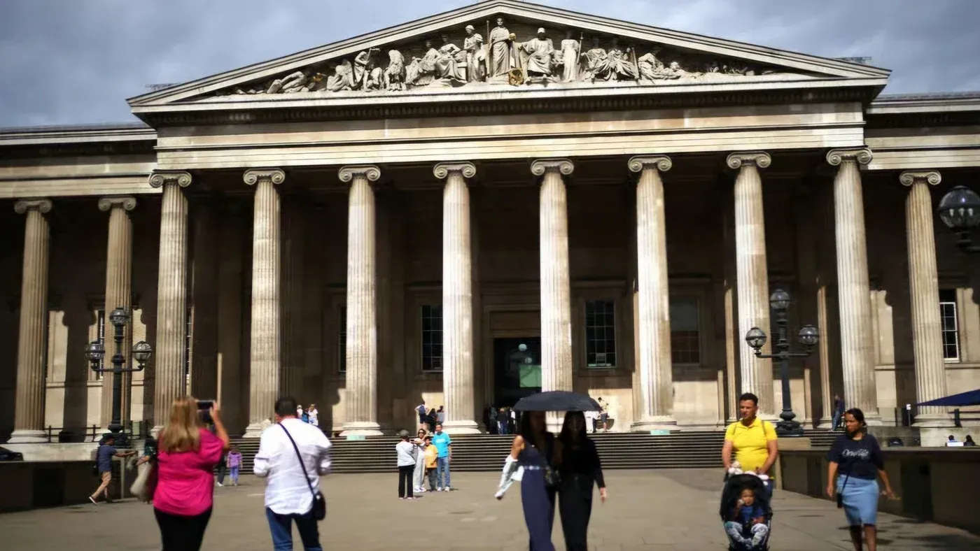 واجهة المتحف البريطاني، تظهر الأعمدة الرخامية والتماثيل، مع زوار يتجولون في الساحة. تعكس الصورة الجدل حول إزالة الإشارات إلى فلسطين.