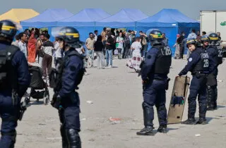 مركز احتجاز للمهاجرين في أوروبا، مع تواجد قوات الأمن، وخلفهم خيام ومهاجرين في انتظار الإجراءات القانونية.