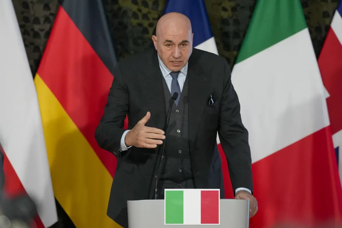 وزير الدفاع الإيطالي جيدو كروسيتو يتحدث خلال مؤتمر صحفي، مع خلفية تضم أعلام الدول الأوروبية.