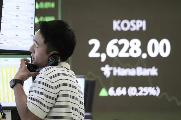 متداول يتحدث في الهاتف أمام شاشة تعرض مؤشر كوسبي في سيول، مع ارتفاع طفيف بنسبة 0.25% إلى 2,628.00.