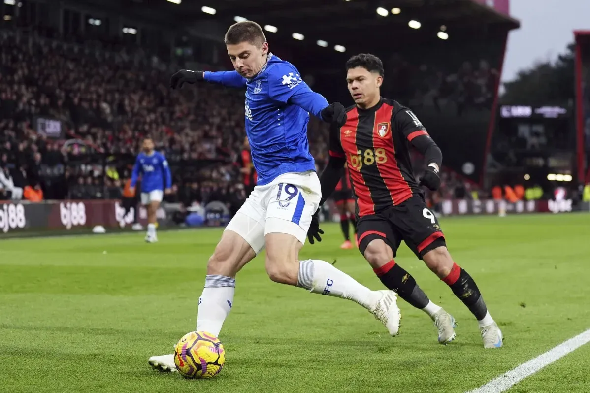 لاعب إيفرتون يتجه نحو الكرة خلال مباراة ضد بورنموث، مع لاعب منافس يطارده، وسط أجواء حماسية في الملعب.
