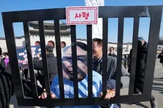 محتج يحمل لافتة تمثل الرئيس الكوري الجنوبي المعزول يون سوك يول خلف قضبان، تعبيرًا عن رفض الحكم الصادر بحقه بتهمة التمرد.