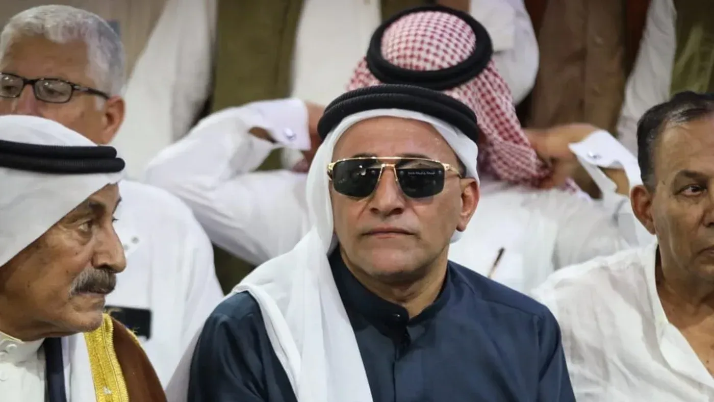 إبراهيم العرجاني، الزعيم القبلي المصري، يرتدي نظارات شمسية ويجلس وسط مجموعة من الرجال في مناسبة اجتماعية، مع التركيز على دوره في السيطرة على مساعدات غزة.