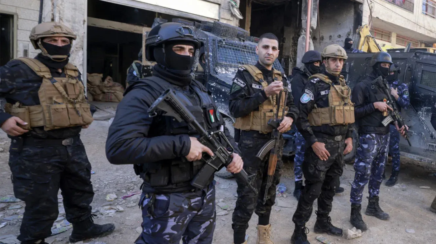 عناصر من الأمن الفلسطيني يرتدون ملابس عسكرية ويحملون أسلحة، يظهرون في موقع قريب من مبانٍ متضررة، مما يعكس الوضع الأمني في غزة.