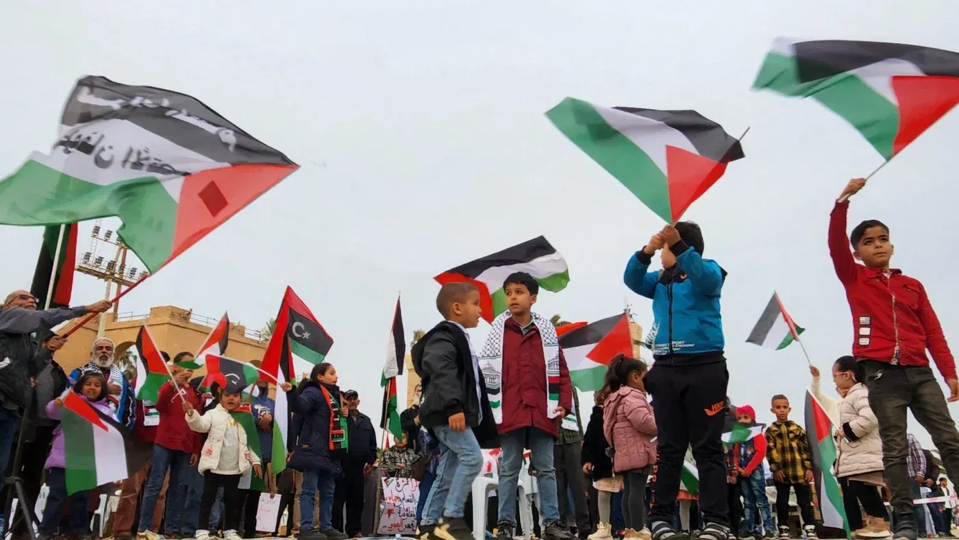 تجمع أطفال وراشدون يحملون الأعلام الفلسطينية في مظاهرة تعبيراً عن دعمهم للقضية الفلسطينية في ليبيا.