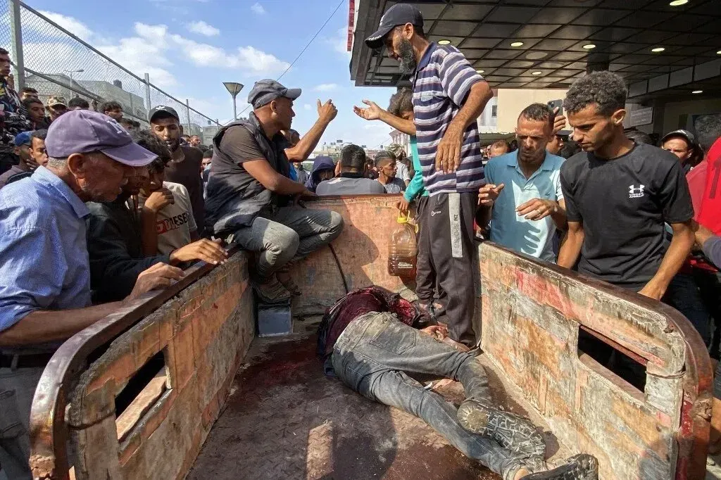 محتشدون حول شاحنة تحمل جثة رجل ملطخة بالدماء في وسط غزة، بينما يبحثون عن معلومات حول المساعدات الإنسانية المفقودة.
