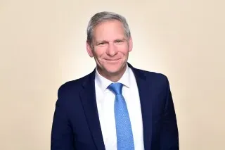 ستيف شلايشر، محامٍ متمرس، مبتسم في صورة رسمية، يرتدي بدلة زرقاء وربطة عنق زرقاء، يعكس خبرته القانونية في قضايا حقوق الإنسان.