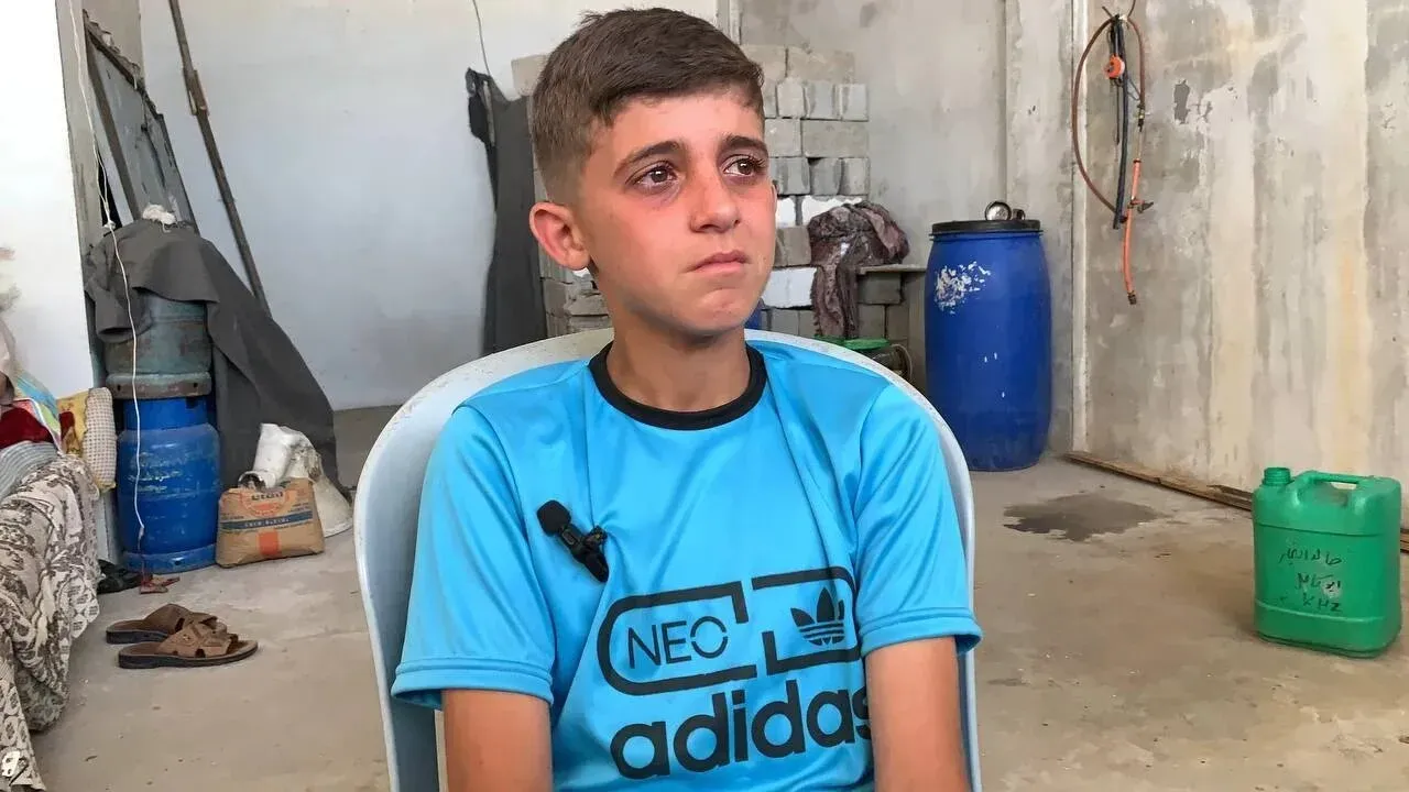 صورة لمحمد أحمد كامل سرحان، البالغ من العمر 13 عامًا، يجلس في غرفة بسيطة، مع تعبير حزين على وجهه، يعكس معاناته بعد غارة إسرائيلية على منزله في خان يونس.