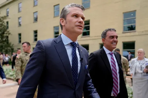 رجلان يرتديان بدلات رسمية يسيران معًا في منطقة خارجية، مع وجود أفراد عسكريين في الخلفية، في سياق حكم قانوني يتعلق بشركة أنثروبيك.