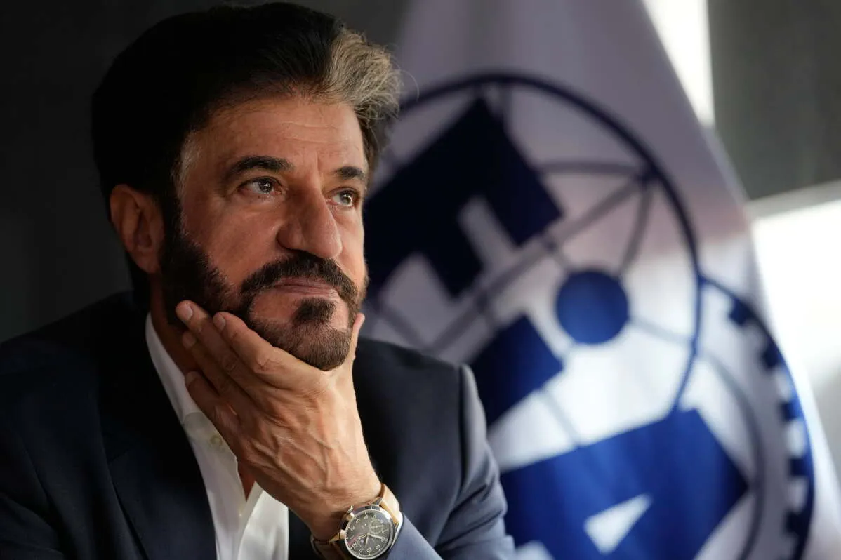 محمد بن سليم رئيس الاتحاد الدولي للسيارات يتأمل بجدية مع شعار الفورمولا 1 في الخلفية وسط توترات أمنية تؤثر على تقويم سباقات الشرق الأوسط.