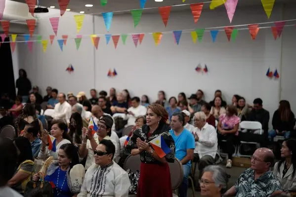 احتفال بجمعية الفلبينيين في حدث ثقافي، حيث يتواجد الحضور في قاعة مزينة بالأعلام وأعلام الفلبين، مع تفاعل حيوي من المشاركين.