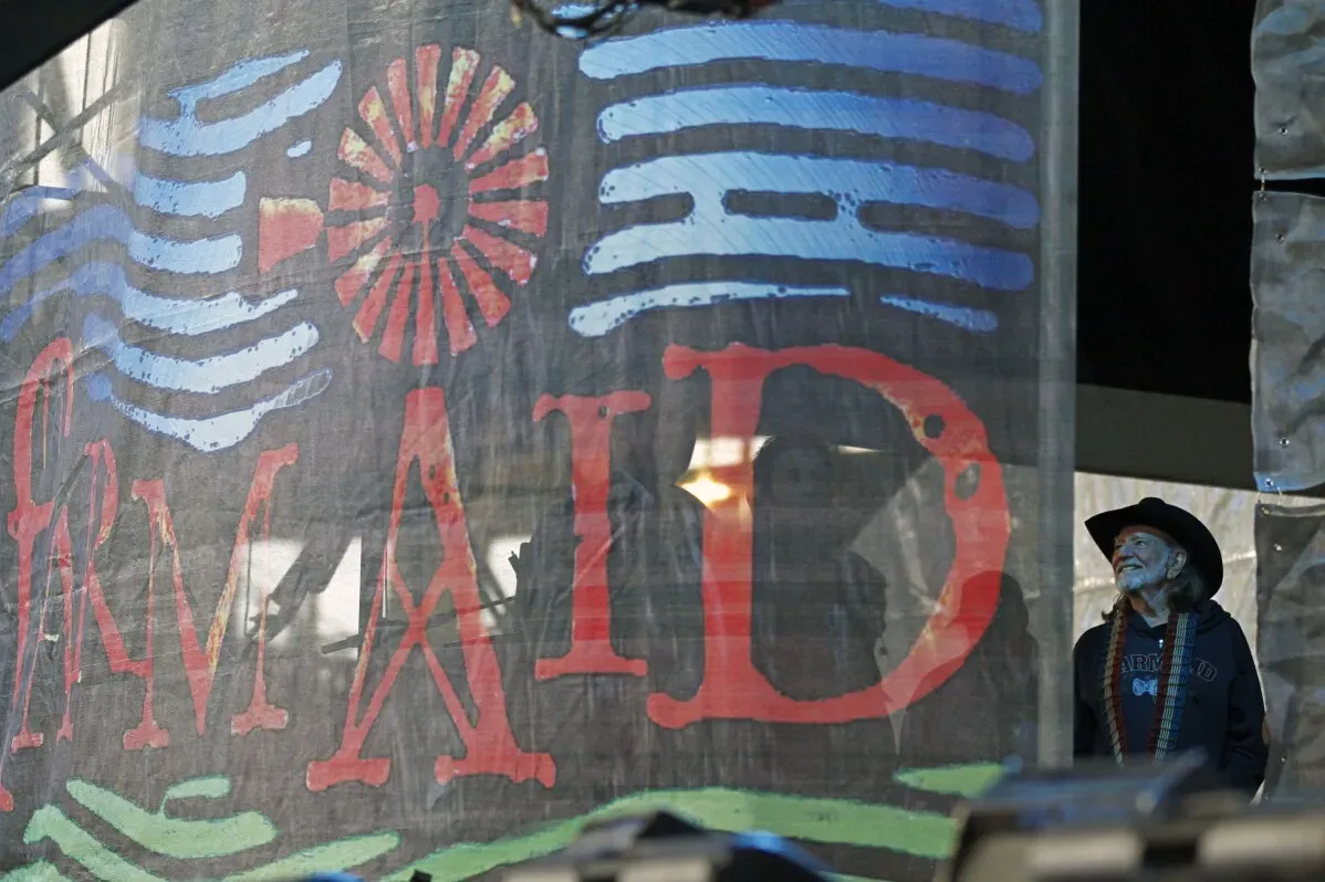 ملصق فعالية "Farm Aid" أمام الفنان ويلي نيلسون، يُبرز جهود الحفل لجمع التبرعات لدعم المزارع العائلية في الولايات المتحدة.