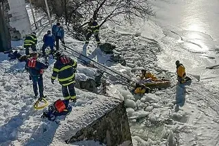 رجال الإطفاء يرتدون بدلات الإنقاذ أثناء إنقاذ بجعة عالقة في نهر متجمد بكونيتيكت، مع وجود جليد حولهم.