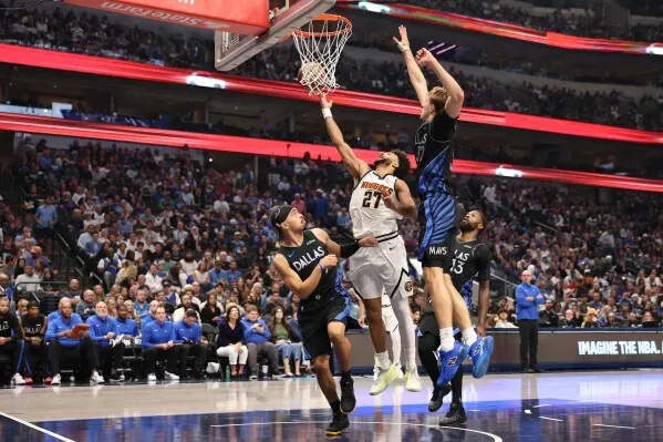 لاعب دنفر ناجتس يسجل نقطة تحت السلة وسط لاعبي دالاس مافريكس خلال مباراة مثيرة انتهت بفوز مافريكس 131-130.