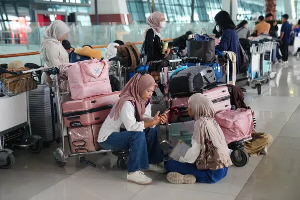 مسافرون ينتظرون في مطار إندونيسي مع أمتعتهم وسط تأخير الرحلات بسبب ثوران بركان Anak Krakatau وتأثيره على النقل الجوي.
