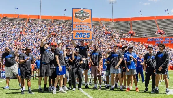 احتفال فريق جاتورز بفوزهم ببطولة NCAA في ملعب فلوريدا، مع عرض لافتة "أبطال الوطن 2025" وحضور جماهيري كبير.