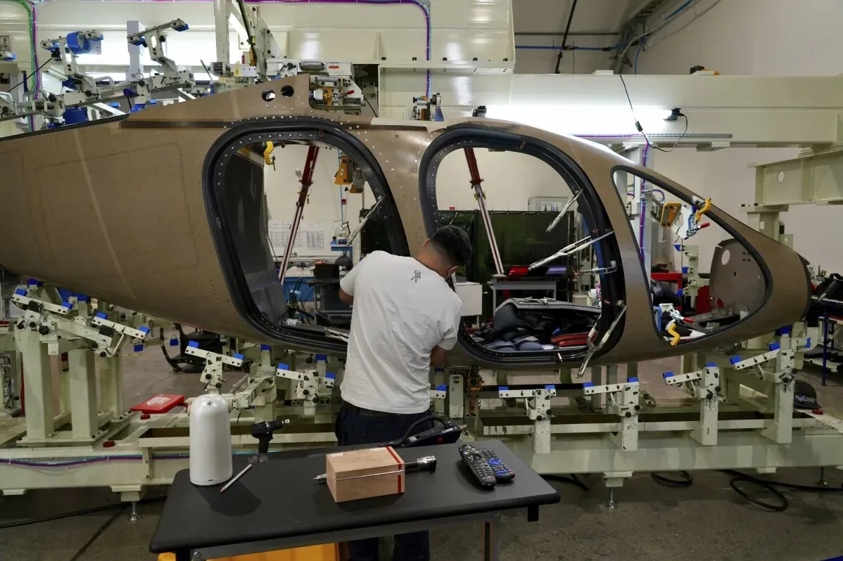 عامل يعمل على تجميع هيكل طائرة eVTOL في ورشة، مع معدات حديثة وخلفية صناعية، تمثل تقدم التكنولوجيا في النقل الجوي.