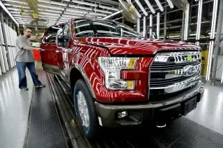 شاحنة Ford F-150 حمراء في مصنع، مع عامل يقوم بفحصها، في إطار سحب 1.4 مليون سيارة بسبب خلل في ناقل الحركة.