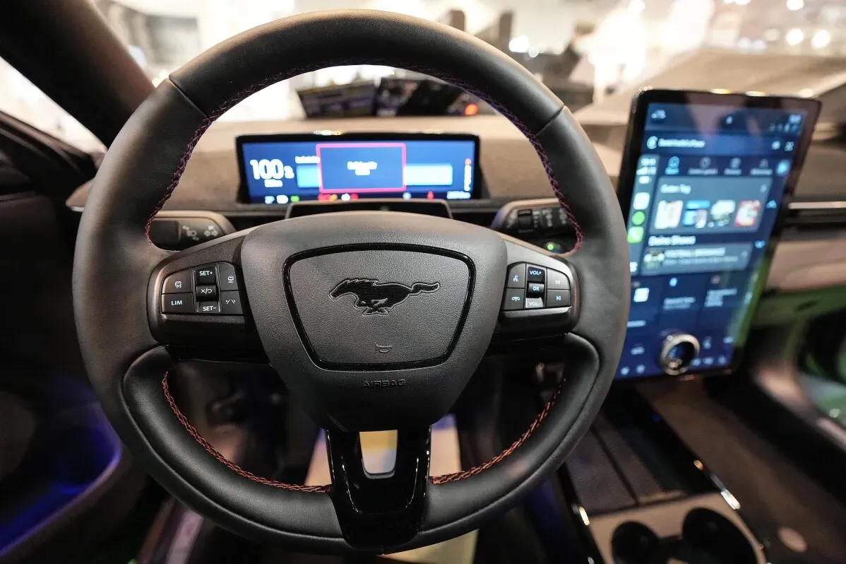 عجلة قيادة سيارة فورد Mustang الكهربائية، تظهر شاشة معلوماتية رقمية تعرض بيانات الأداء، مع تصميم داخلي عصري.