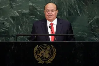 تظهر الصورة عبد ربه منصور هادي، الرئيس اليمني السابق، وهو يتحدث أمام منصة الأمم المتحدة، مع خلفية خضراء.