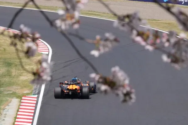 سيارة سباق مكلارين تسير على حلبة سوزوكا، محاطة بأزهار الكرز، خلال التجارب النهائية لسباق جائزة اليابان الكبرى للفورمولا 1.