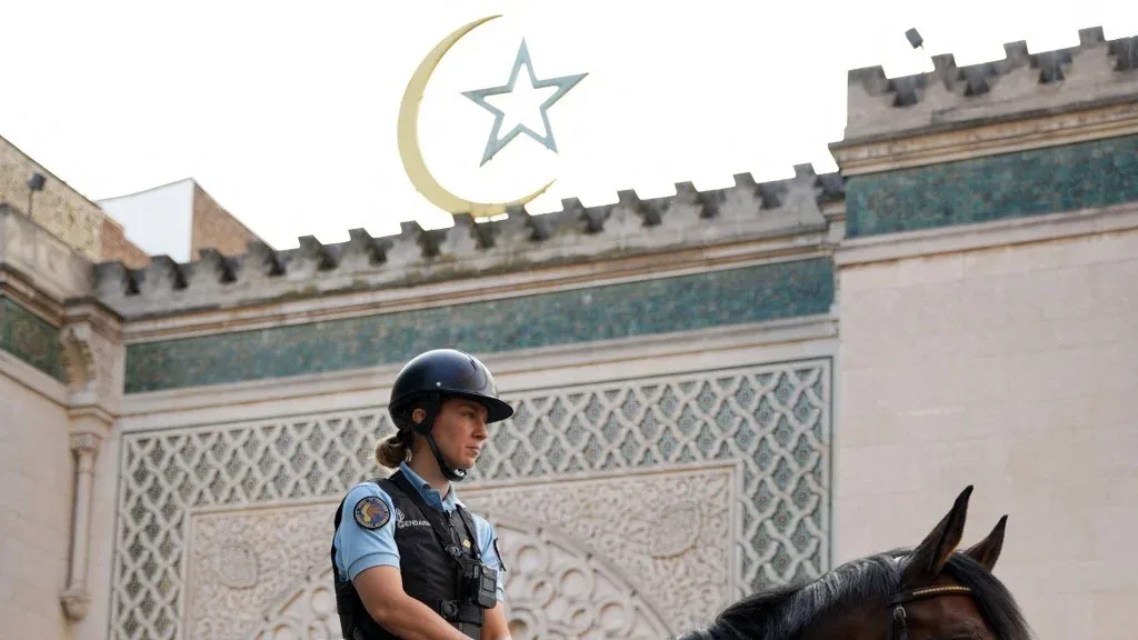 شرطي فرنسي على حصان أمام مسجد مغلق قرب باريس، يعكس توترات حرية العبادة والقيود على المساجد الإسلامية في فرنسا.
