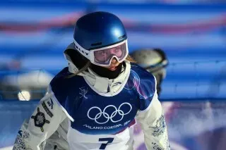 إيلين غو، المتزلجة الصينية، تتزلج في دورة الألعاب الأولمبية الشتوية، مرتدية زي المنافسة، وتظهر تركيزها بعد جولة قوية.