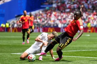 لاعب كرة القدم البلجيكي جيريمي دوكو يتعرض لعرقلة خلال مباراة في كأس العالم، مع تواجد لاعبين آخرين في الخلفية.